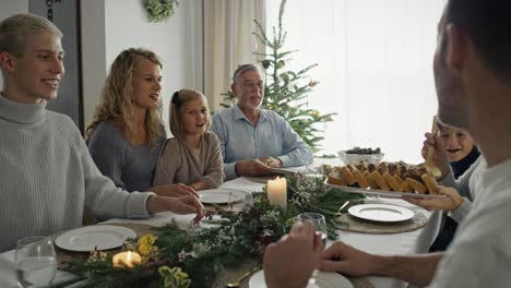 Familia-Caucásica-Sentada-Alrededor-De-La-Mesa-Y-Pasando-La-Navidad-Juntos.