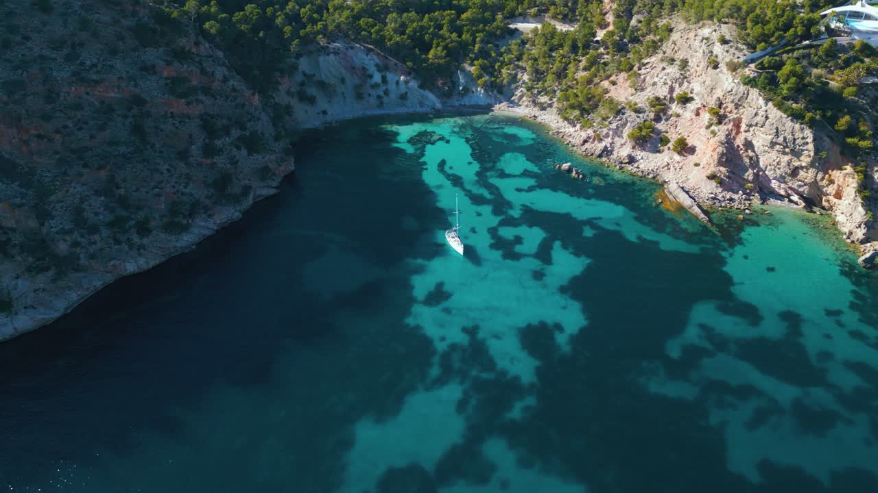 bahía de aguas cristalinas de color turquesa con yate y barco de vela en la isla de palma de mallorca