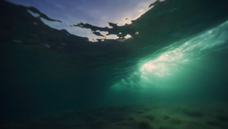 brillantes rayos dorados de luz brillan en la superficie arenosa mientras las olas del océano se rompen