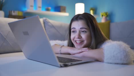una joven feliz y alegre mirando la computadora portátil con atención.