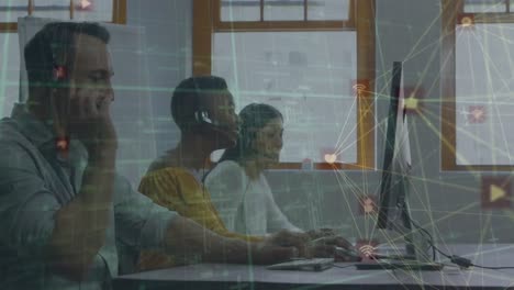 Animation-of-globes-of-digital-icons-over-diverse-colleagues-talking-on-phone-headsets-at-office