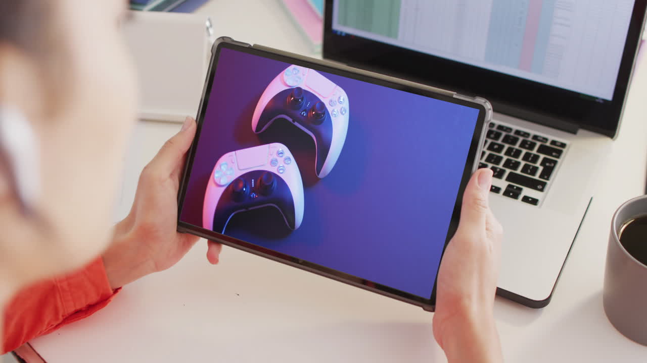 mujer caucásica en el escritorio usando tableta, compras en línea para gamepads, cámara lenta