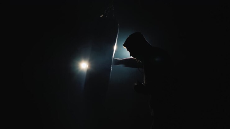 Silhouette di un combattente Trinity in palestra - colpisce un sacco da boxe.