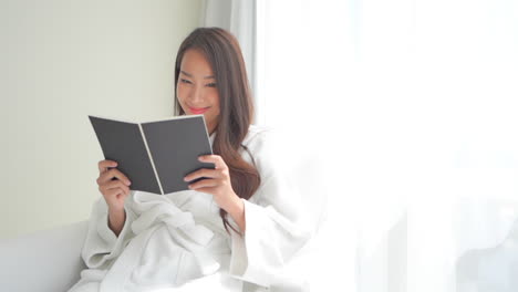 sexy beautiful asian woman in bathrobe relaxing reading book in hotel room