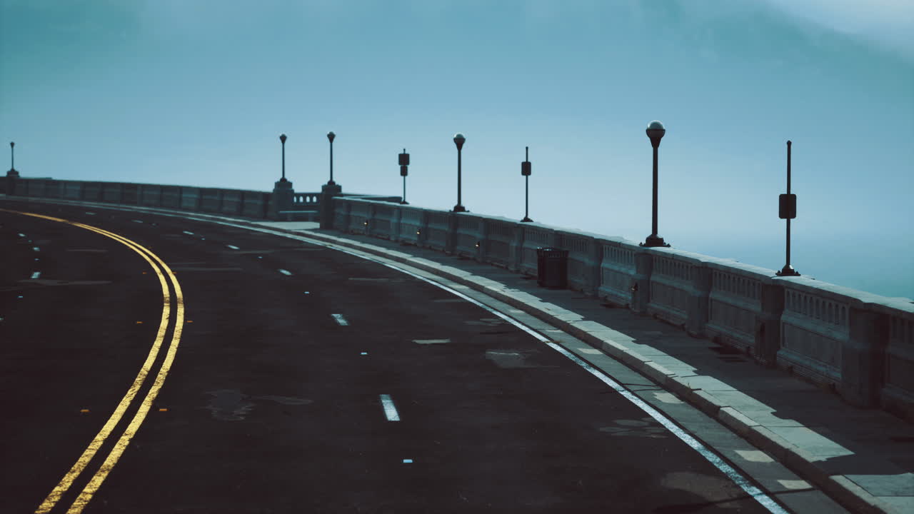 Curved road with streetlamps on a misty morning by the waterfront