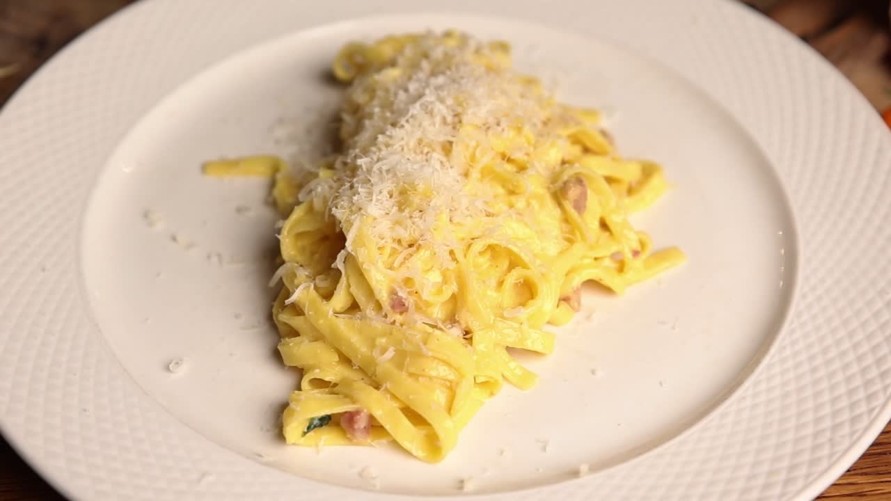 Piatto di Pasta Carbonara Cremosa Guarnito con Parmigiano Grattugiato