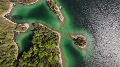 The-top-down-aerial-perspective-of-Eibsee,-Grainau,-Germany,-where-vibrant-lake-waters-intertwine-with-forest-covered-small-islands