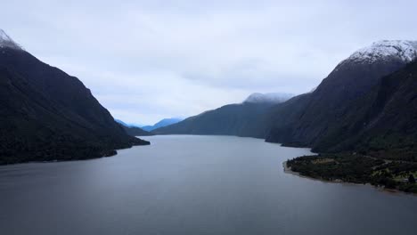 Dolly-out-aerial-view-of-Tagua-Tagua-Lake-with-snowy-and-cloudy-mountains-on-the-side,-southern-Chile