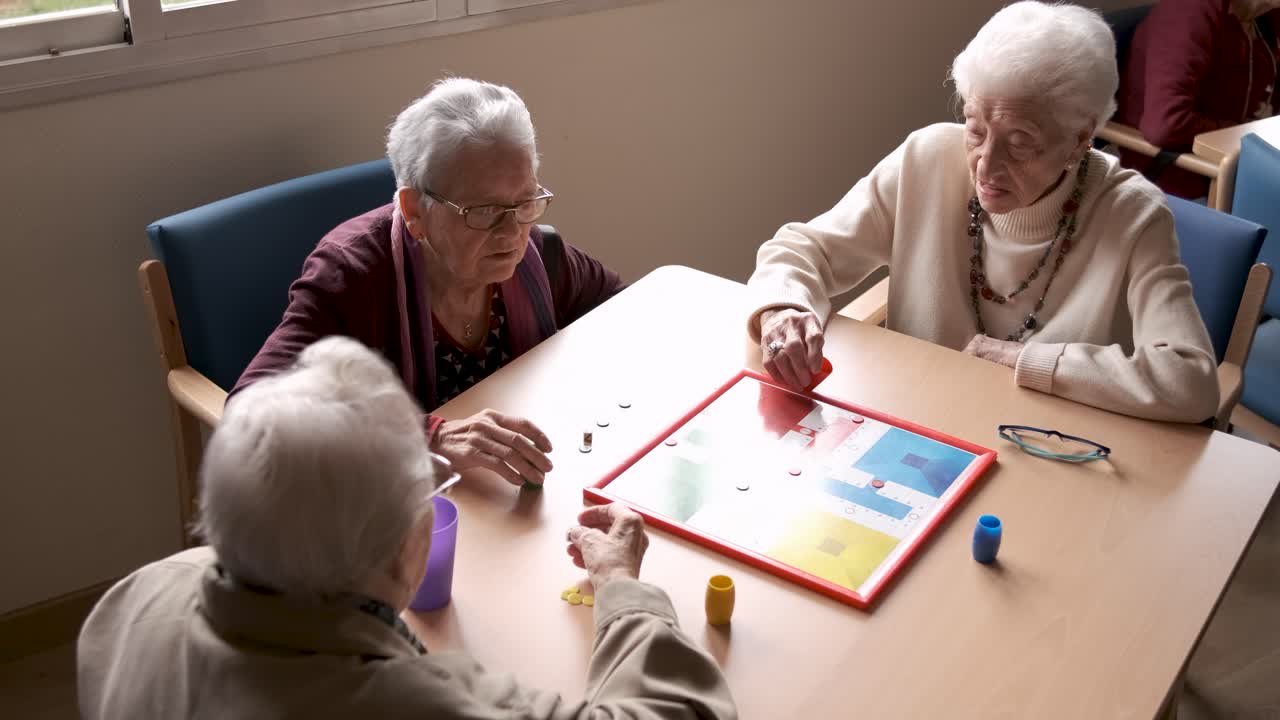 Senior friends playing ludo in nursing home canteen
