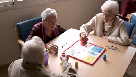 senior friends playing ludo in nursing home canteen