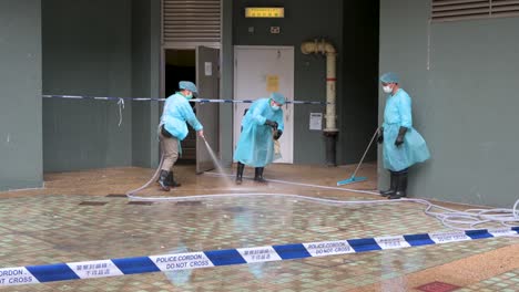 health workers disinfect the street outside a building placed under lockdown after a large number of residents tested positive in hong kong