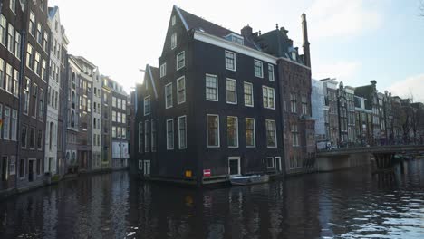 cámara inclinada hacia arriba de las casas junto al río de ámsterdam que muestran el encanto urbano a lo largo del pintoresco centro de la ciudad