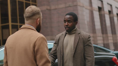 rear view of a caucasian man talking and disputing with african american man, they are arguing and one of them turning and going away