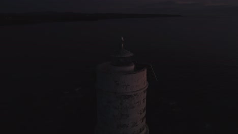 Toma-Aérea-Cinematográfica-De-La-Luz-Del-Faro-Parpadeando,-Pájaro-Gaviota-En-La-Parte-Superior,-Anochecer