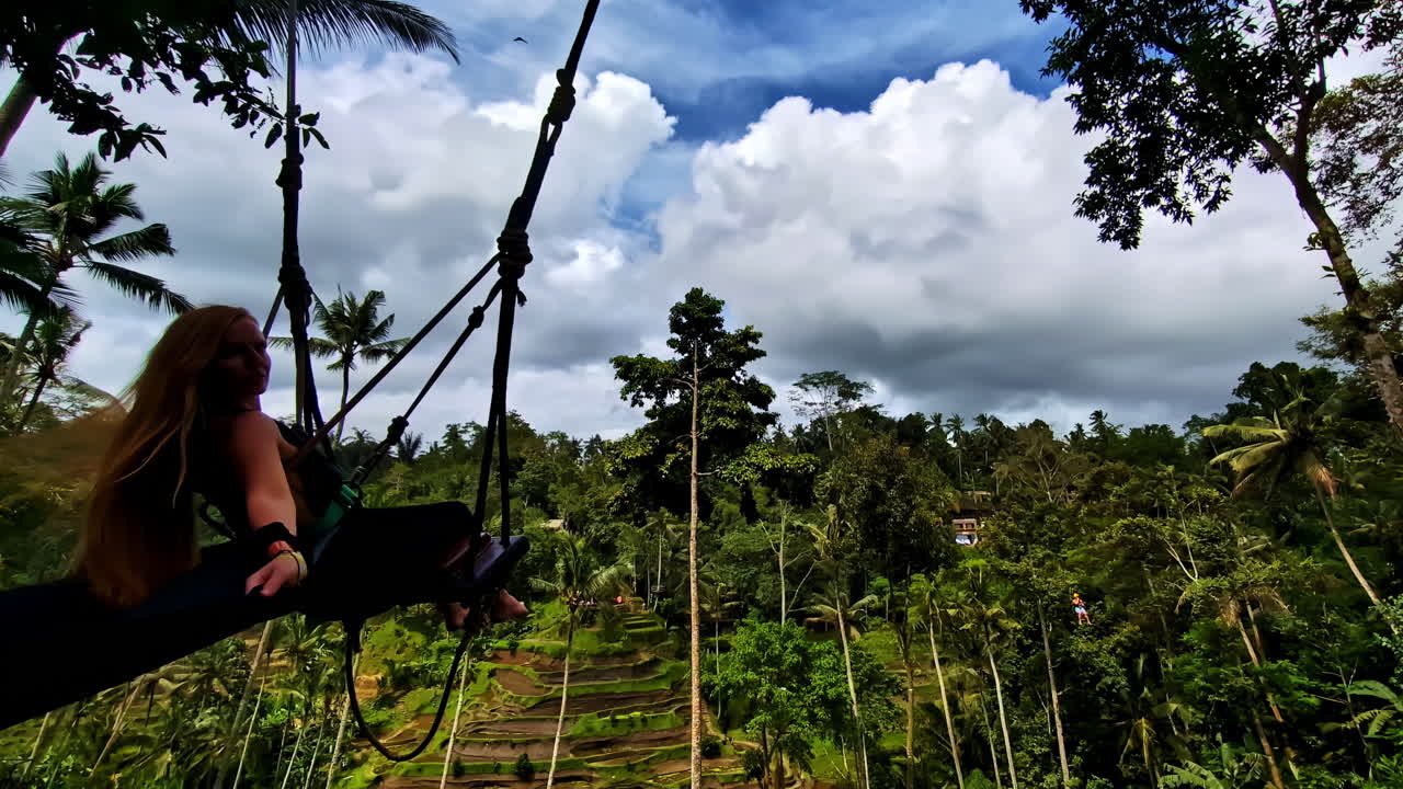 Una persona che si dondola sopra le terrazze di riso di Tegallalang a Bali, mostrando bellezza naturale e avventura.
