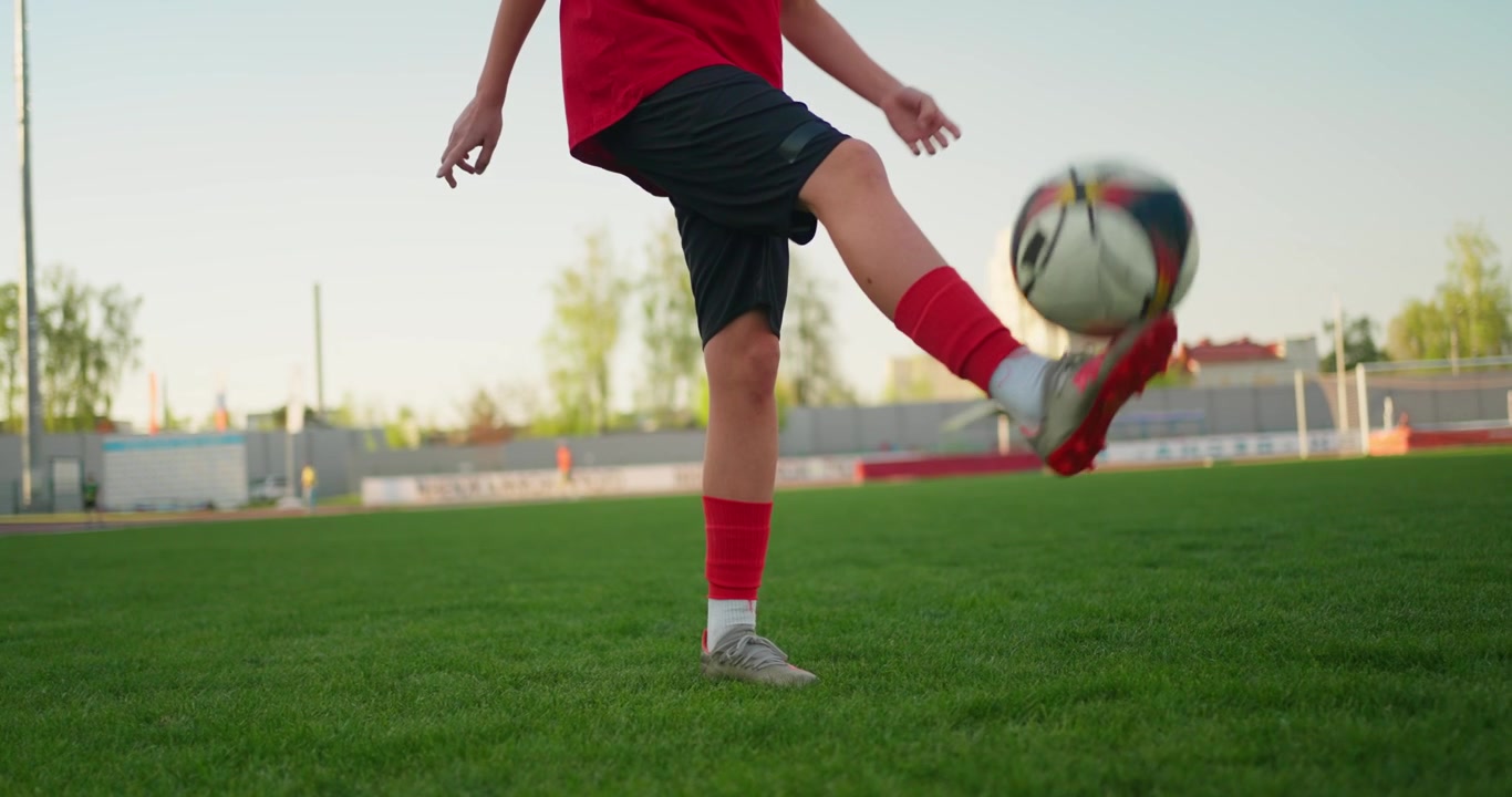 Joven futbolista dominando el balón en un campo de césped verde
