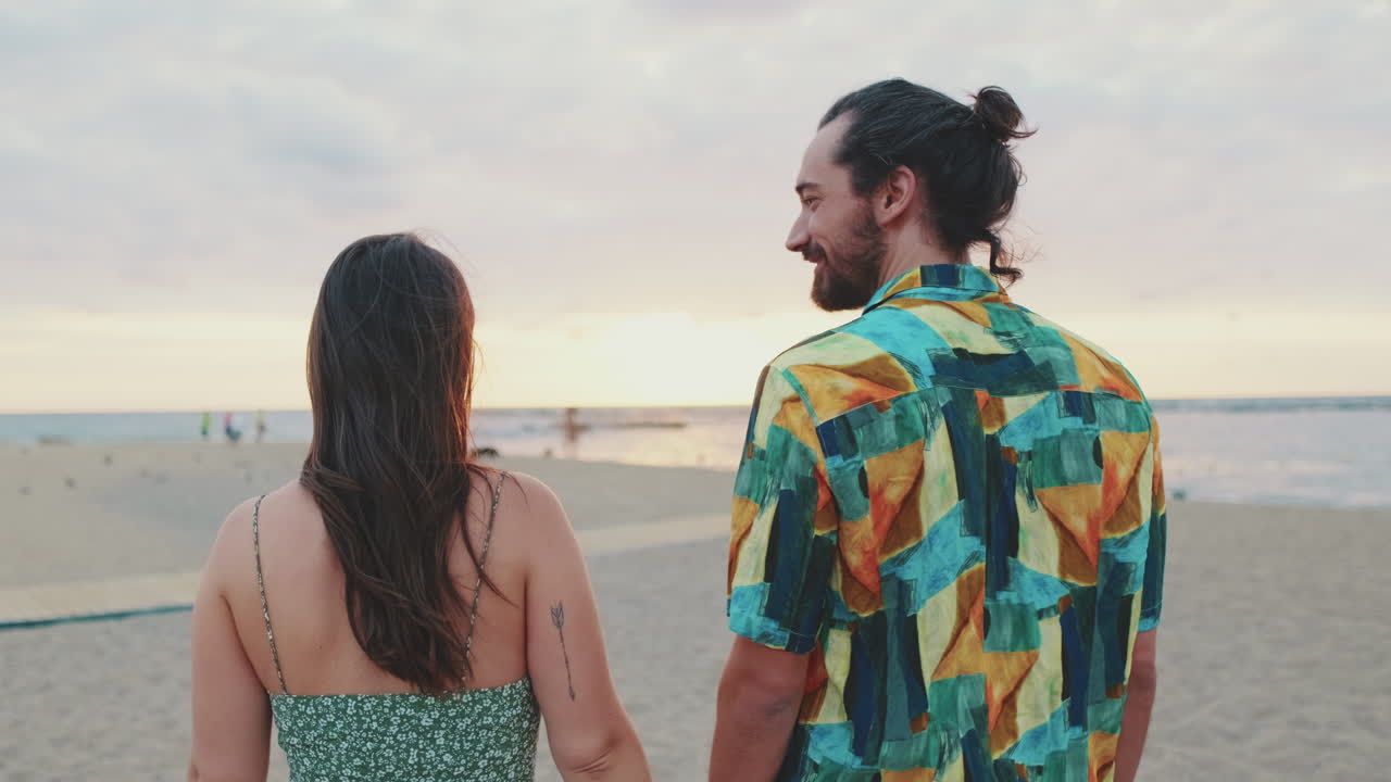 pareja tomados de la mano en la playa al atardecer