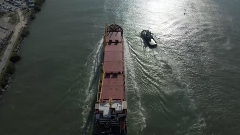 Barco-Navegando-Hacia-El-Puerto,-Horizonte-De-La-Ciudad-En-El-Fondo,-Inclinación-Aérea-Hacia-Arriba