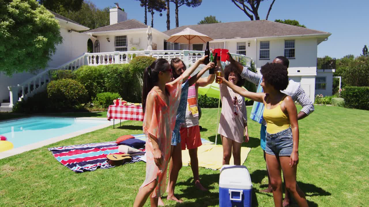 Groupe d'amis diversifié portant un toast lors d'une fête à la piscine