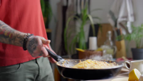 tossing pasta in skillet while frying
