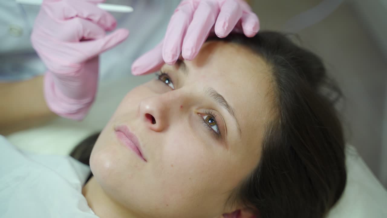 master is making a permanent eye makeup for a woman in a beauty salon. Equipment for permanent makeup