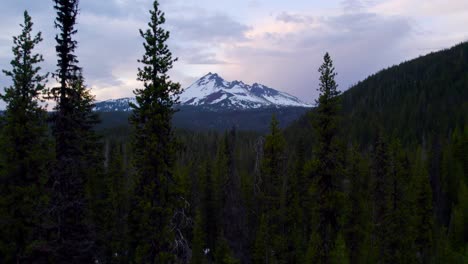 broken top mountain at sunset. drone flying through trees toward snow capped peak. 4k.