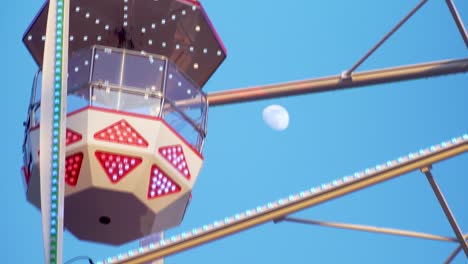 Ferris-Wheel-Attraction-Spinning-with-Moon-Background,-Getting-Dawn,-Close-Up