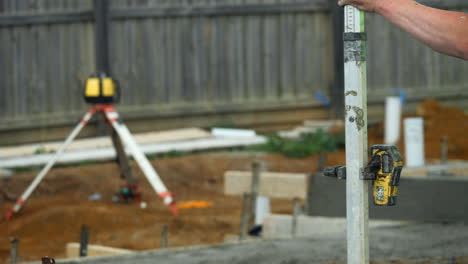 worker checks new cement slab construction with rotating laser level