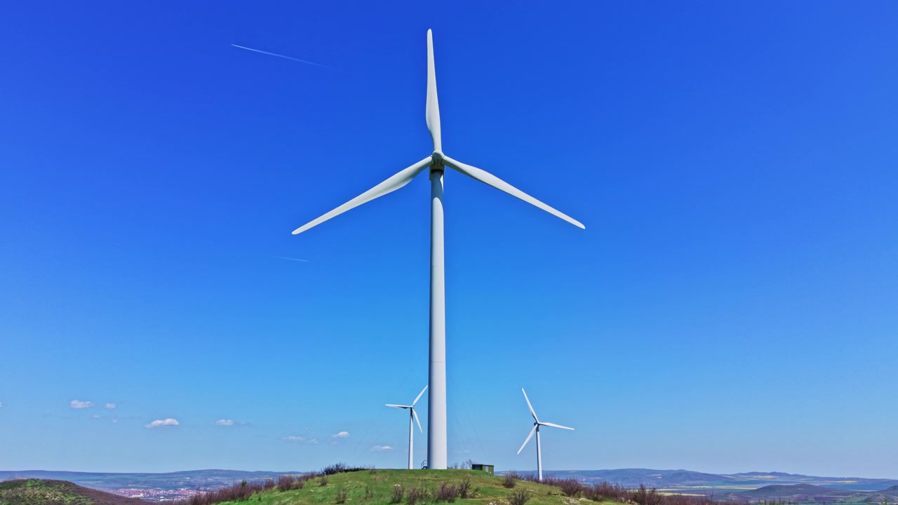 Un ingegnere controlla il funzionamento delle turbine eoliche sotto un cielo sereno in una giornata di sole in un parco eolico.