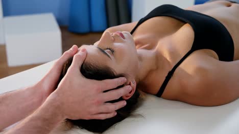 fisioterapeuta masculino dando masaje de cabeza a una paciente femenina