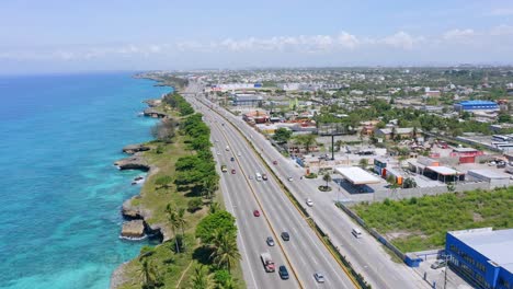 drone shot of driving vehicles on freeway along coastline of santo domingo city during summer