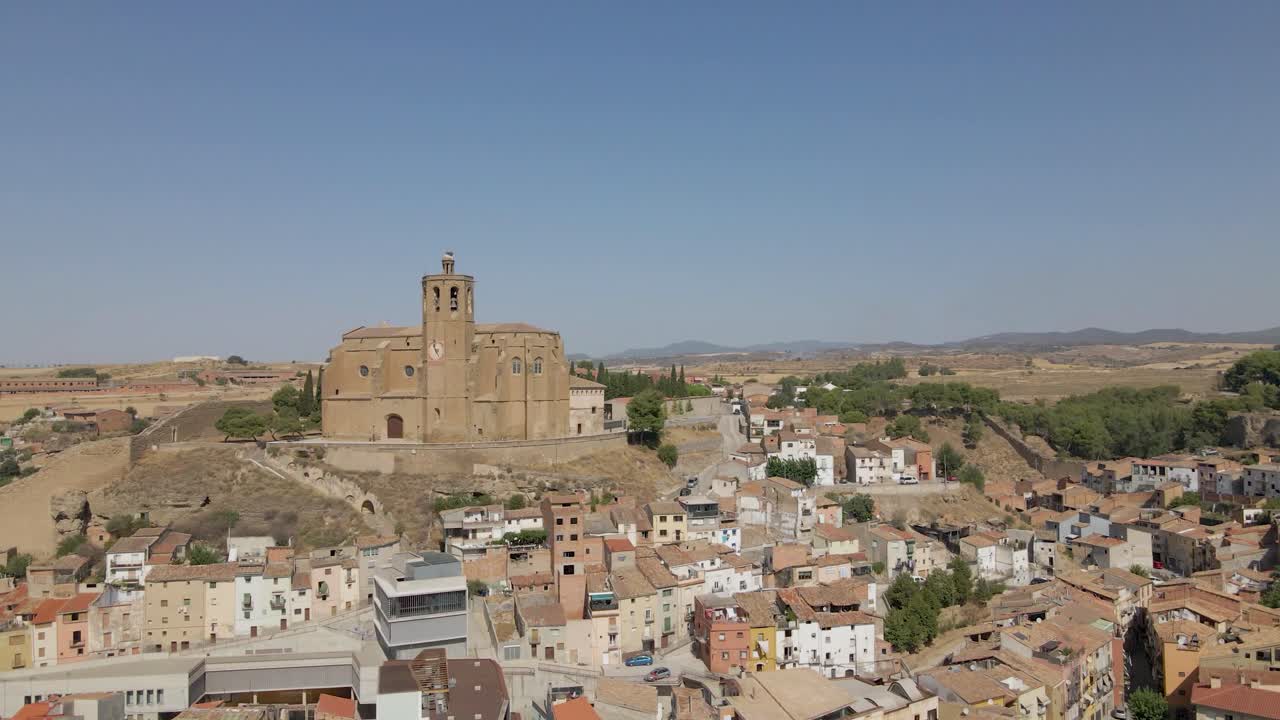 An enchanting circular drone shot of the Catholic Church Santa Maria de Balaguer in Lleida, Spain, basking in the golden afternoon sun