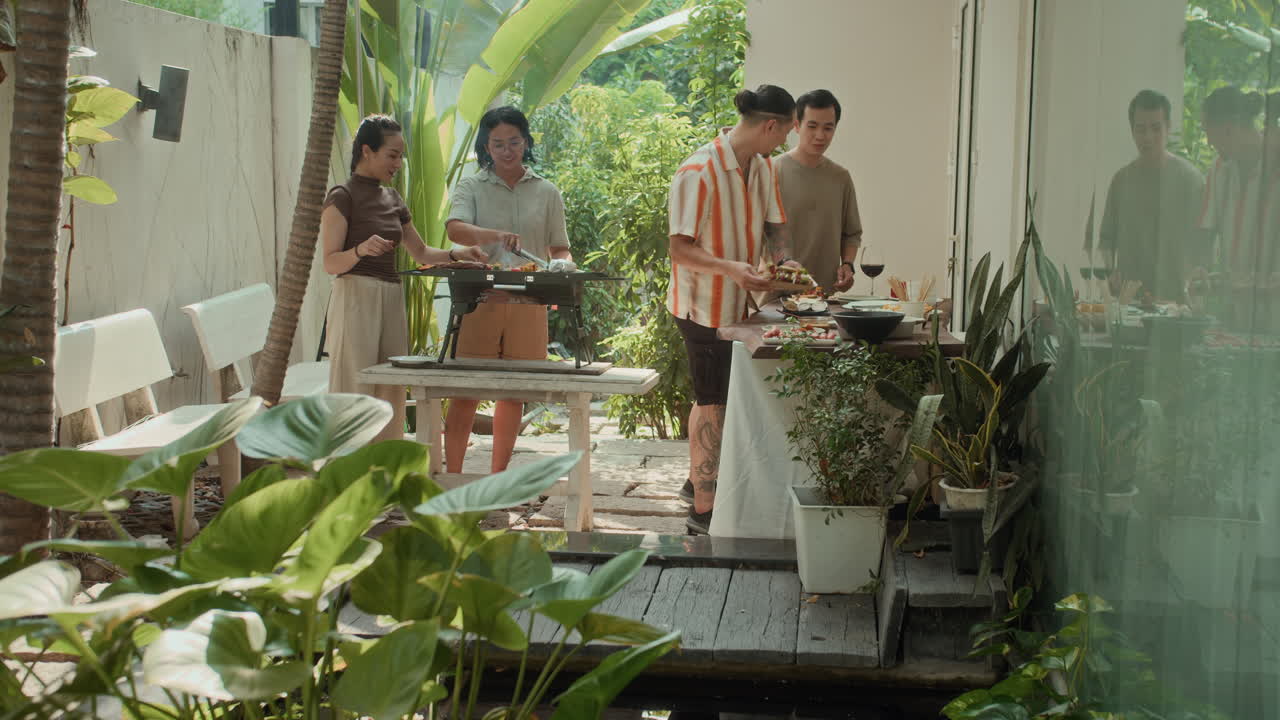 Friends Helping with Barbecue during Outdoor Party