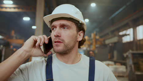 worker in safety hard hat having phone talk in industrial factory