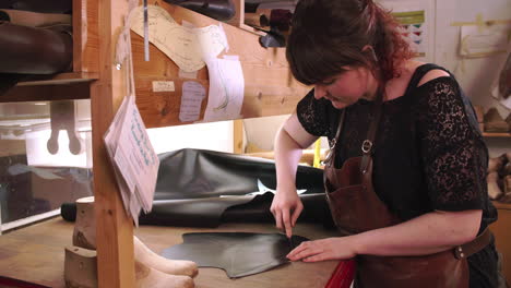 bespoke shoemaker measuring and cutting leather for shoe