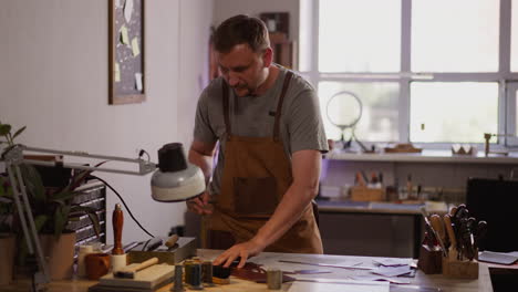 thoughtful man in workwear seeks sharpening tool in shop