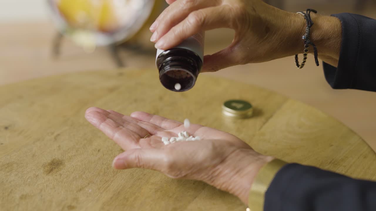 Close-up seseorang menuangkan pil obat ke tangan, melambangkan layanan kesehatan dan pengobatan.