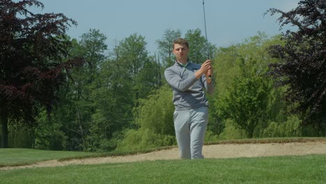 a golfer chips out of a sand trap and celebrates.