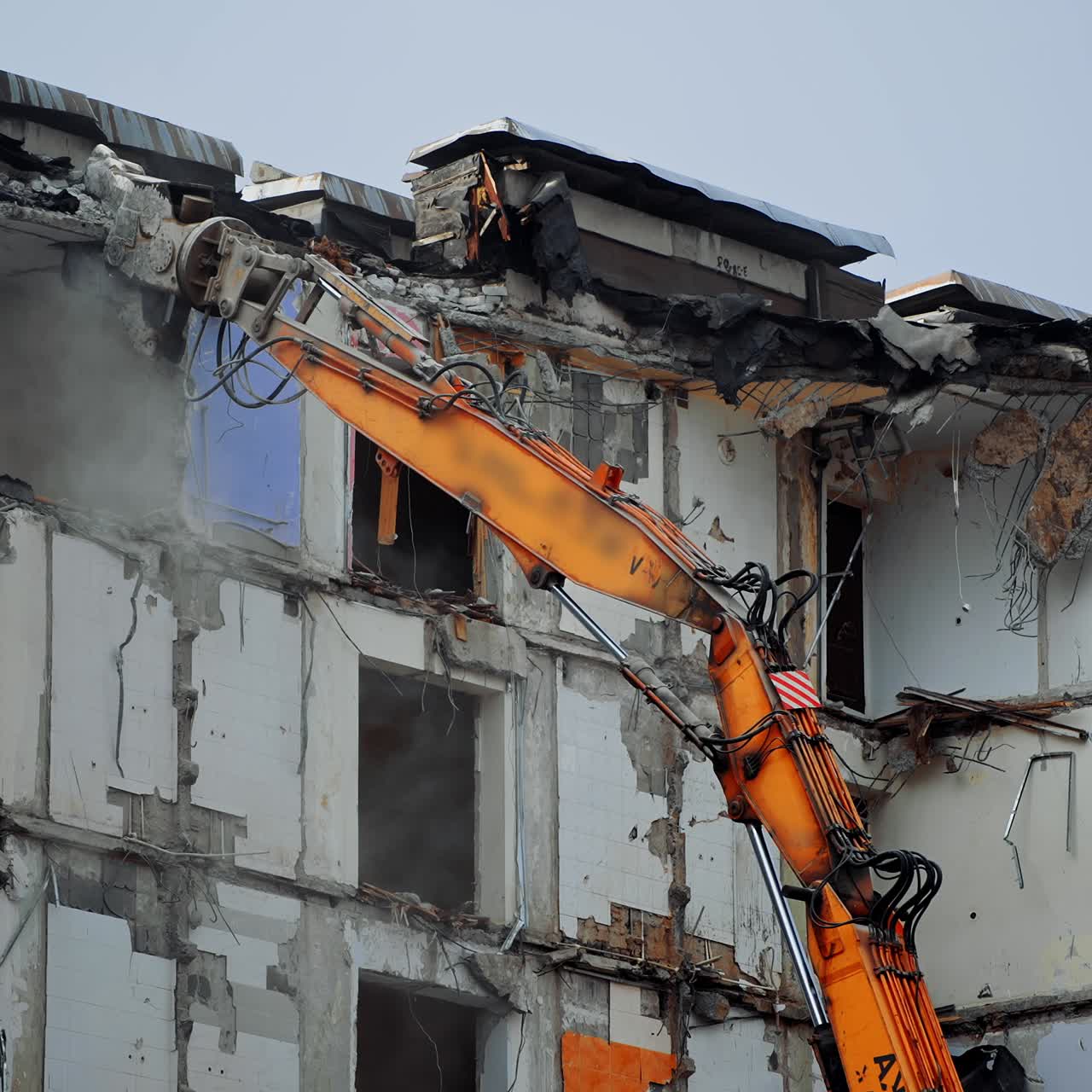 Tall building destroyed by an earthquake. Demolition machine tearing down roof of a wrecked building. Long machine claw pulling down the debris