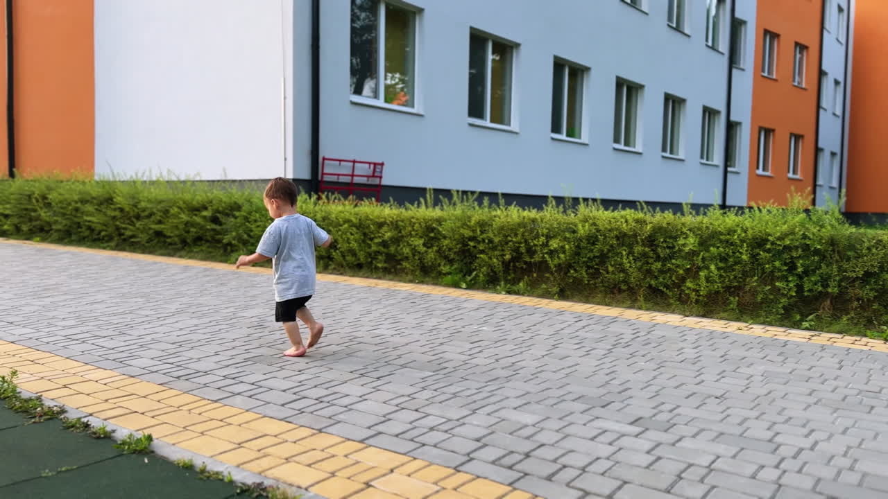 Cute toddler baby running by the road barefoot. Active time-spending outdoors in summer.