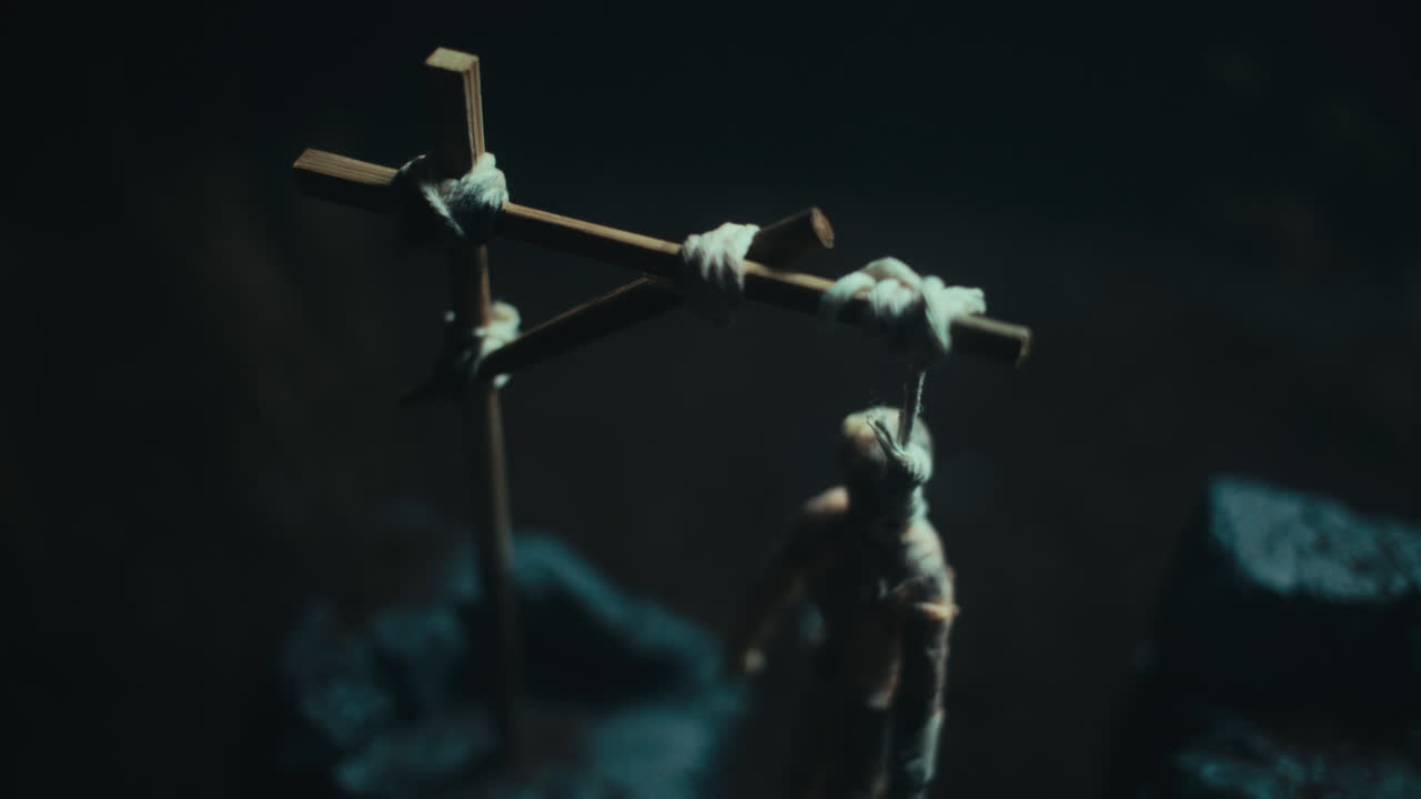 A miniature mummified doll hanging on the gallows at night