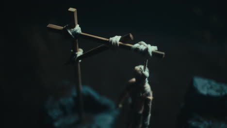 a miniature mummified doll hanging on the gallows at night