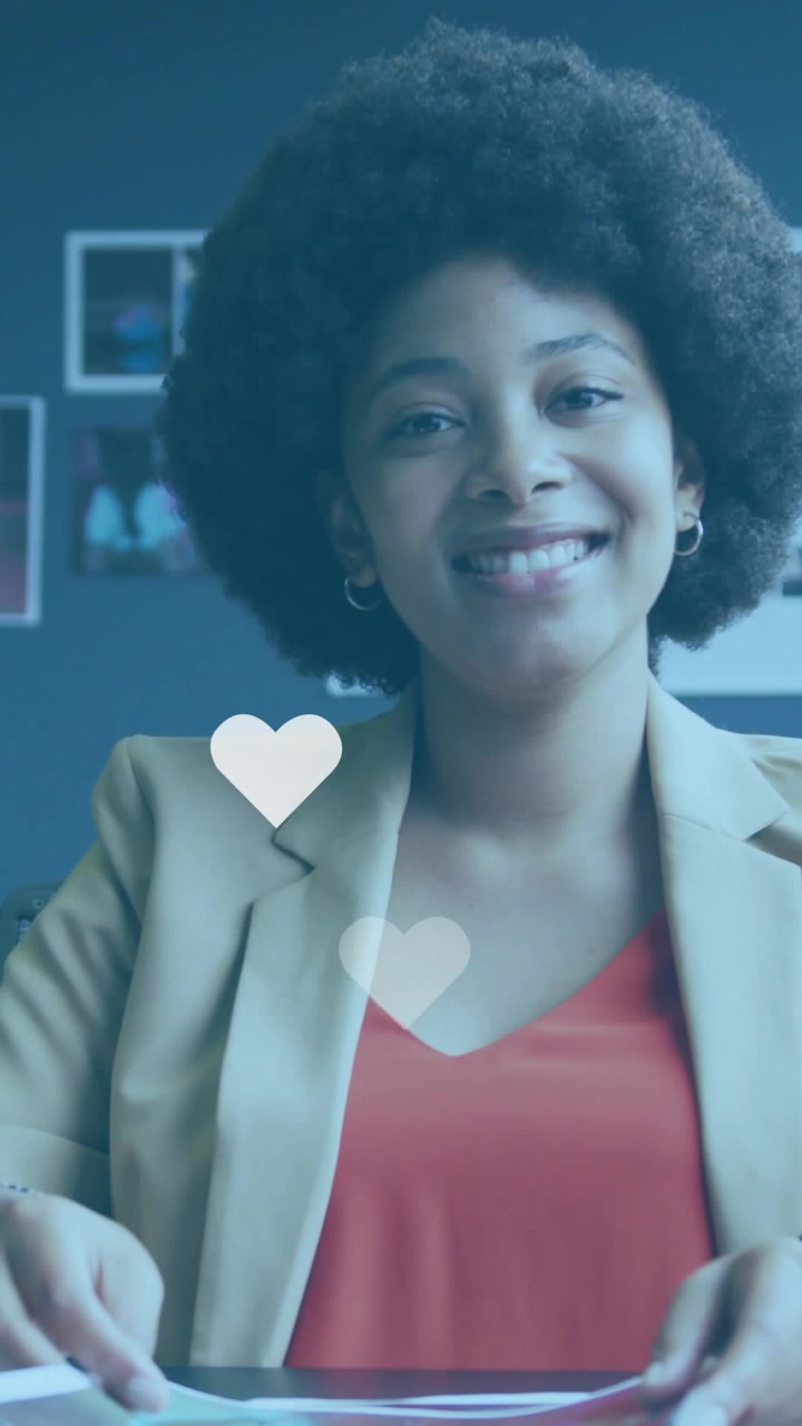 Vertical video: Woman paging papers at desk, hearts rising on cue as tapping showing doc for promo