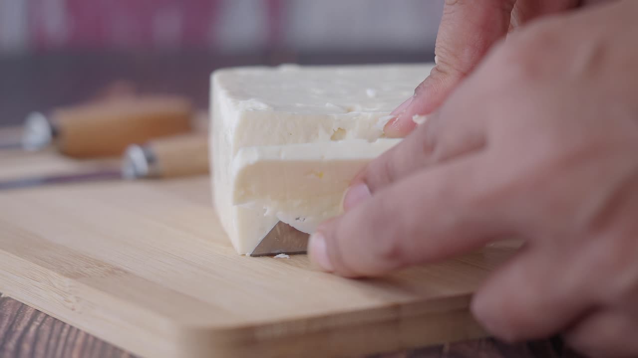 Cheese being cut on a cutting board