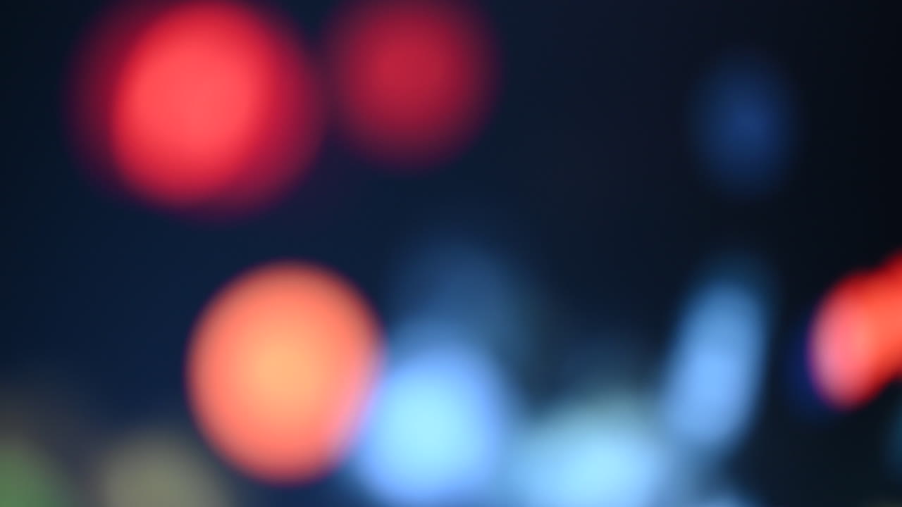 Luci bokeh astratte in rosso, blu e giallo su sfondo scuro.
