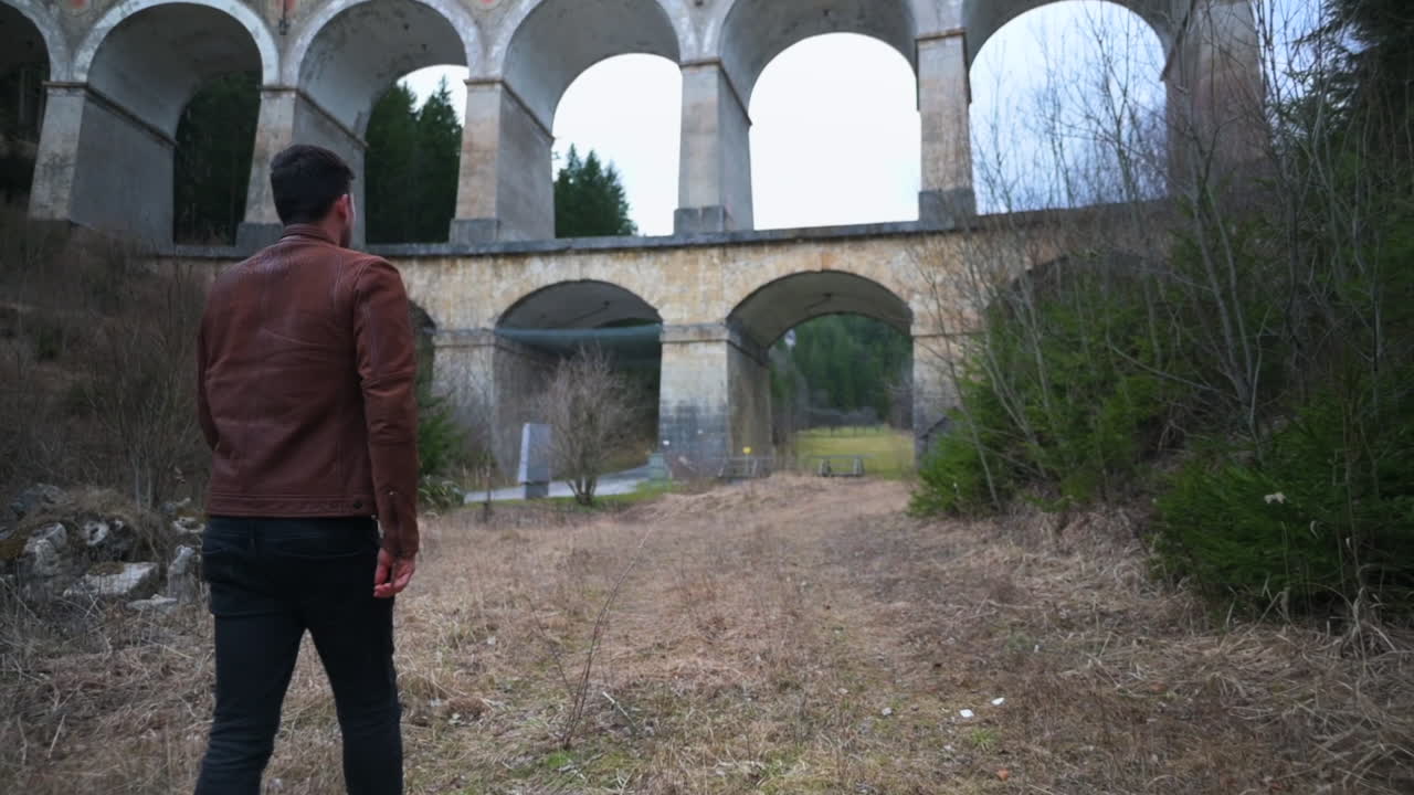 Man Walking Away from Old Stone Arch Bridge