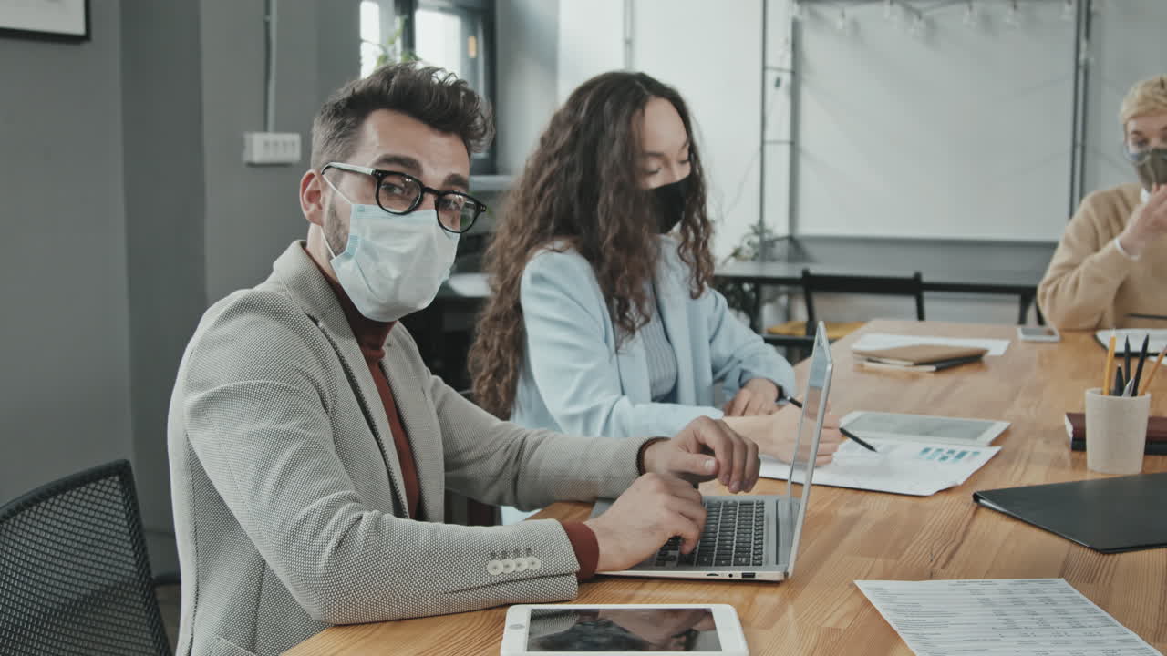Empresario con mascarilla trabajando en un portátil