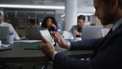 Seriöser-Geschäftsmann-Sucht-Auf-Einem-Tablet-Nach-Diagrammdiagrammen-Für-Ein-Firmenmeeting.