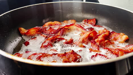 Experimente-El-Fascinante-Chisporroteo-Del-Tocino-Frito-En-Una-Sartén,-Capturando-La-Esencia-Del-Placer-Del-Desayuno-Con-Delicioso-Detalle