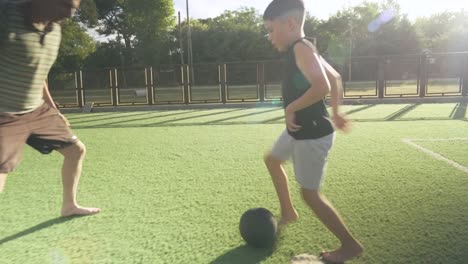 loving father playing soccer with young son, sharing joyful moment on synthetic grass field during bright summer day